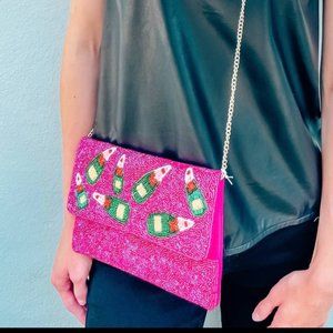 This beaded crossbody and clutch has a beaded champagne bottle accent pattern